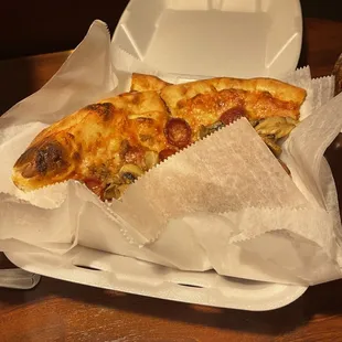 a slice of pizza in a styrofoam container