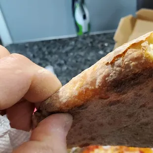 a hand holding a half eaten pizza