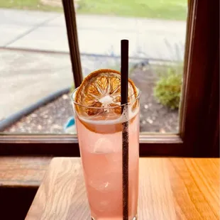 a pink drink with a straw and a slice of lemon