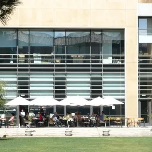 the outside of the building with tables and umbrellas