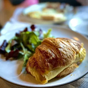 Buttered croissant with egg and ham with salad