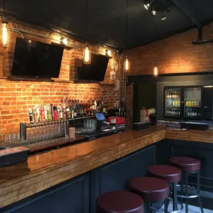 a bar with red stools and a brick wall