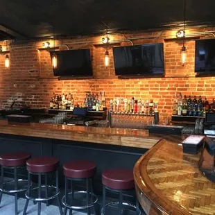 a bar with red stools and a brick wall