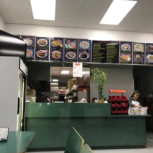 a restaurant counter with menus on the wall