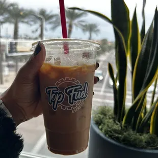 a hand holding a cup of iced coffee