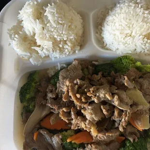 a styrofoam container with rice, meat and vegetables