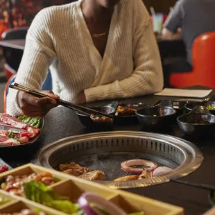  a woman sitting at a table with plates of food and chopsticks
