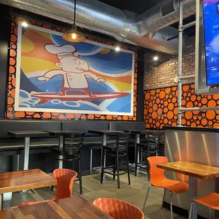 a bar with orange chairs and a large painting on the wall