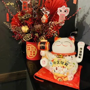 a vase of flowers and a cat figurine