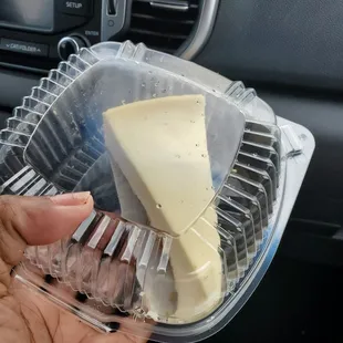 a hand holding a piece of cheese