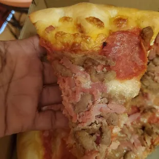 a hand holding a slice of pizza