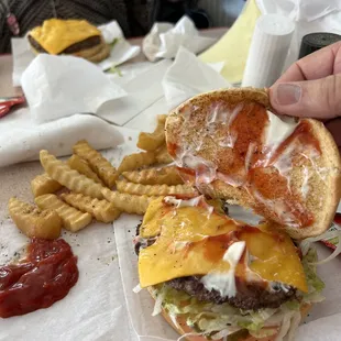 ows a hand holding a cheeseburger and fries