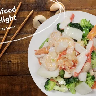 a plate of shrimp and broccoli with chopsticks