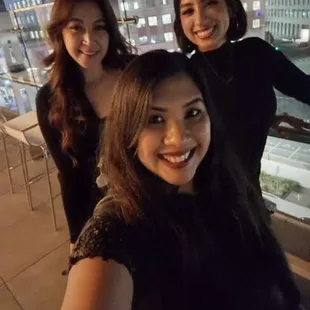 three women taking a selfie on a rooftop at night