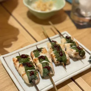 a plate of skewered food on a wooden table