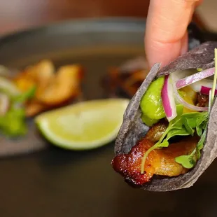 The Al Pastor Pork Belly Tacos are served with yuzu avocado sauce.