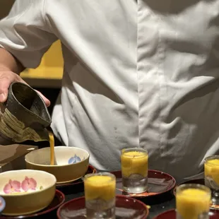a man pouring orange juice into a bowl