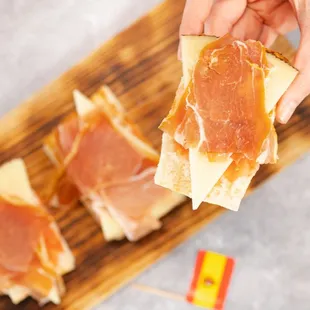 a person holding a piece of ham