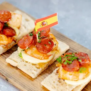 a wooden cutting board topped with crackers and a small spanish flag