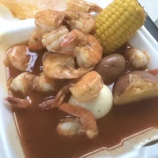 shrimp, potatoes, and corn on a styrofoam container