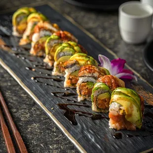 a long row of sushi with sauce and chopsticks