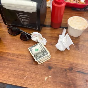 a person sitting at a table with money and a cup of coffee
