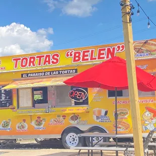 a yellow food truck with a red umbrella