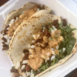 two tacos in a styrofoam container