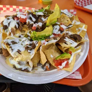 Nachos carne asada. Crema, frijoles refritos, queso, crema, tomate y jalapenos. $9.50.