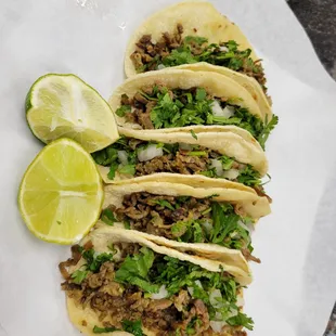 a plate of tacos with lime wedges