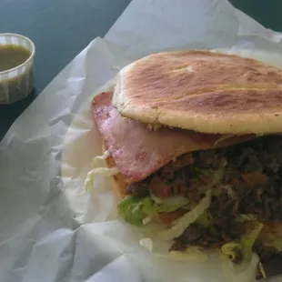 Steak, Ham, &amp; cheese torta with refried beans &amp; green and red salsa.