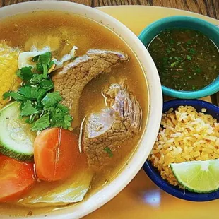 a bowl of soup, corn, and vegetables