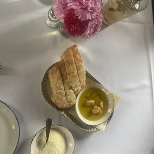 a table setting with bread, olive oil, and flowers