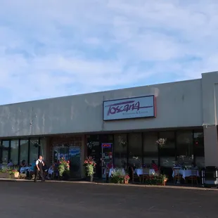 Strip mall storefront, with a lot of patio tables in use at the moment.