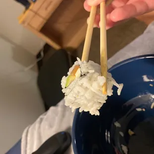 a person holding chopsticks over a bowl of rice