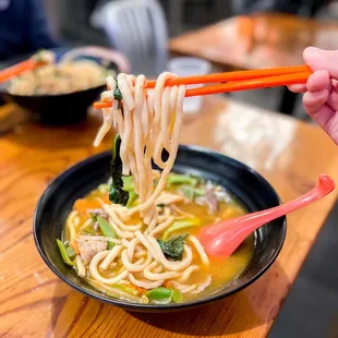 a bowl of noodles with chopsticks