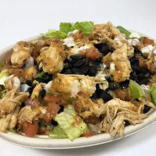 a salad with chicken, lettuce, tomatoes, and black beans