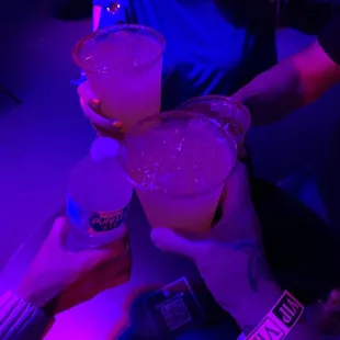 a woman holding two margaritas