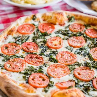 a pizza with tomatoes and spinach