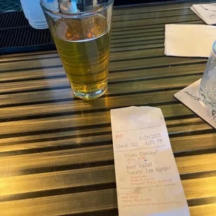 a glass of beer and a receipt on a table