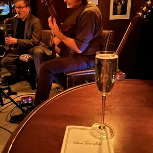 a man playing a guitar and a glass of wine