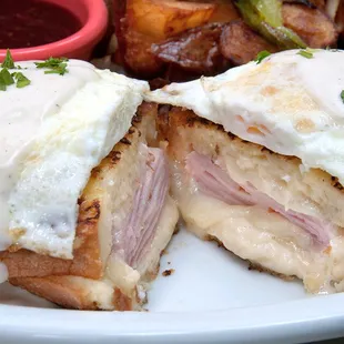 MADAME CRISTO Our Famous French Toast stuffed with ham and Swiss cheese then topped with two over-medium eggs with creamy béchamel and chipo