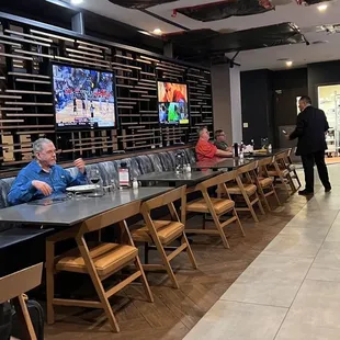 people sitting at tables and watching televisions