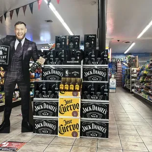a man in a suit standing in front of a display of liquor