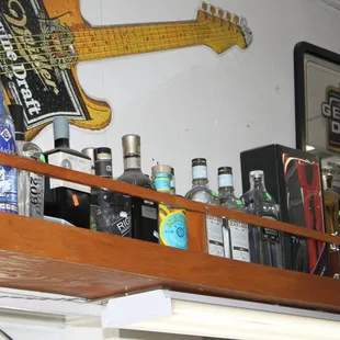 a shelf of liquor bottles and a guitar