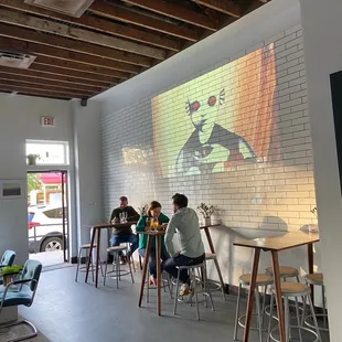 Projection screen behind three high tops