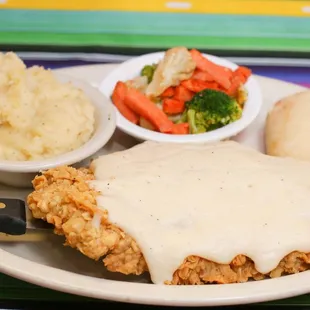 a plate of fried chicken with gravy and mashed potatoes