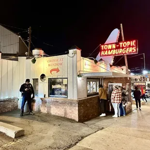 people standing outside of a restaurant at night