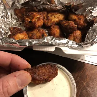 a hand holding a piece of fried chicken