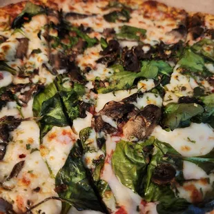 a pizza with spinach and mushrooms
